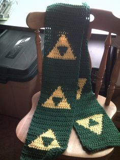 a green crocheted scarf sitting on top of a wooden chair