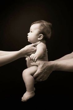 a black and white photo of a baby being held by an adult's hand