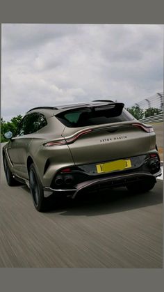 the rear end of a silver sports car driving on a road