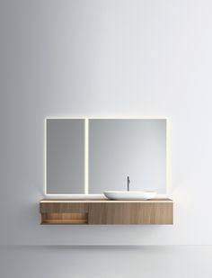 a white sink sitting on top of a wooden counter next to a wall mounted mirror