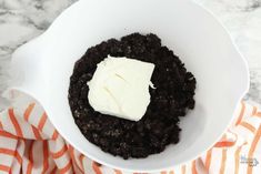 a bowl filled with pudding and cream on top of a tablecloth next to an orange striped towel