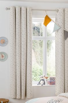 a child's bedroom with polka dot curtains and bedding, including a teddy bear on the window sill