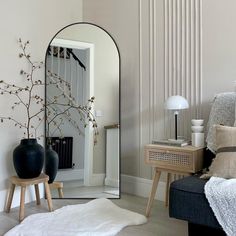 a mirror sitting on top of a wooden table next to a black vase filled with flowers