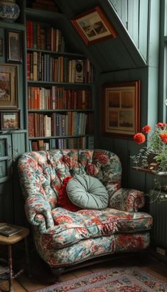 a chair in front of a bookshelf filled with lots of books and flowers