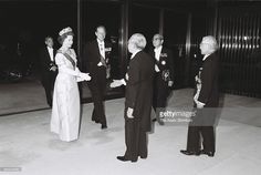 an old black and white photo of people in formal wear talking to each other while standing outside