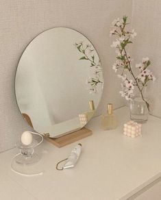 a white dresser topped with a mirror and vase filled with flowers