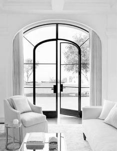 black and white photograph of living room with arched glass door