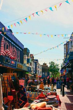 an outdoor market with people shopping in the background and bunting strung across the street