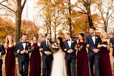 a group of people standing next to each other in front of trees with leaves on them