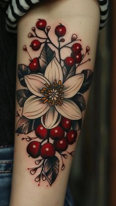 a woman's arm with a flower and berries tattoo on it