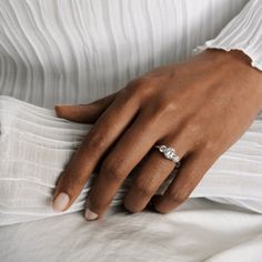 a woman's hand with a diamond ring on her left wrist, resting against a white shirt