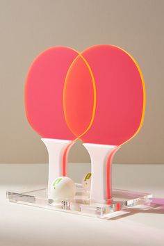 two orange and pink lamps sitting next to each other on a white counter top,