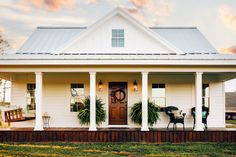 a white house with two porches and potted plants on the front