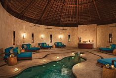 the inside of a spa with blue couches and candles on the floor next to an indoor swimming pool