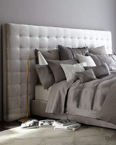 a bed with grey linens and white pillows