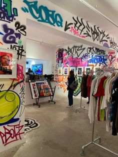 there are many shirts on display in this room with graffiti all over the walls and floor