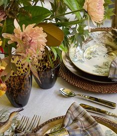 the table is set with plates, silverware and flowers