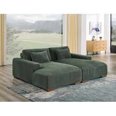 a large green couch sitting on top of a wooden floor next to a window in a living room