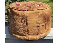 an old leather ottoman sitting on top of a wooden bench