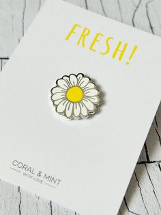 a white and yellow flower pin sitting on top of a card