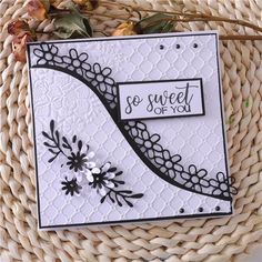 a white card with black and white designs on it sitting in a basket next to some leaves