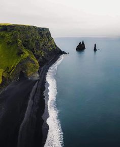 an aerial view of black sand beach and cliffs on the faroen coast, iceland