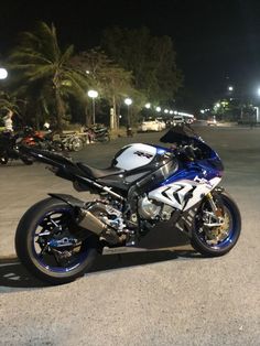 a blue and white motorcycle parked on the side of a road at night with palm trees in the background