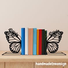 there is a bookend with a butterfly on top of it and four books in front of it