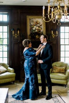 a man and woman standing next to each other in front of a chandelier