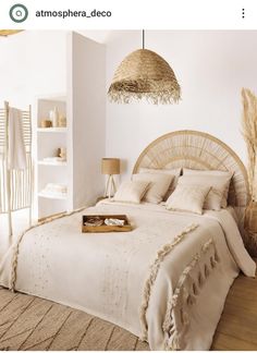 a bed with white linens and pillows in a room next to a wall hanging from the ceiling