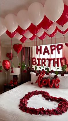 a bed with red and white balloons floating from it's headboard in the shape of a heart