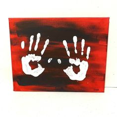 a red and black painting with white hand prints