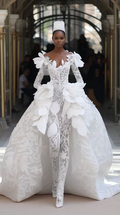 a model walks down the runway in a white gown