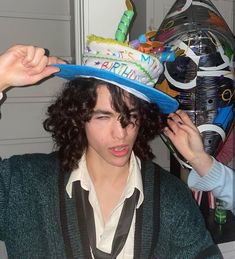 a young man with curly hair wearing a birthday hat