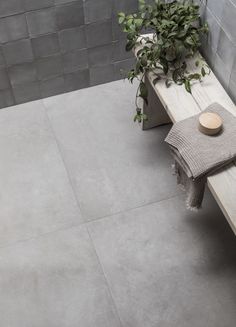 a wooden bench sitting next to a potted plant on top of a tiled floor