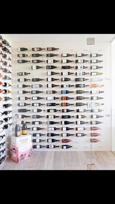 a wine rack filled with lots of bottles on top of a hard wood floor next to a white wall