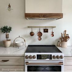 a stove top oven sitting inside of a kitchen next to a counter with pots and pans on it