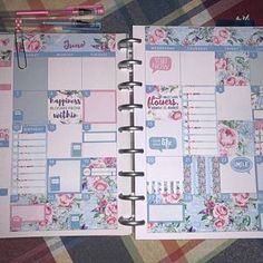 an open planner book with pink flowers and blue accents on the page, next to a pen