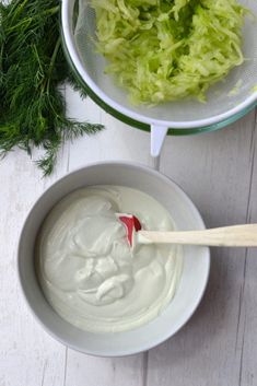 a white bowl filled with green vegetables next to a strainer full of yogurt