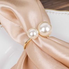 two pearls are sitting on top of a satin napkin with a gold ring in the middle