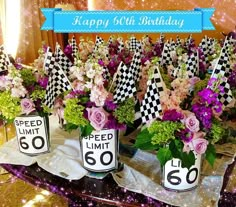 a table topped with lots of vases filled with flowers and racing flags next to each other