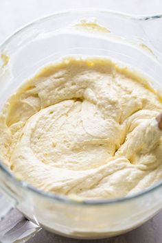 a glass bowl filled with batter sitting on top of a white countertop next to a knife