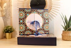 a decorative box with a blue bow sits on a table next to potted plants