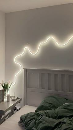 a bed with a green comforter and some white lights on the wall above it