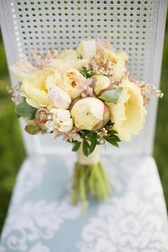 a bouquet of yellow flowers sitting on top of a white chair in front of a green field