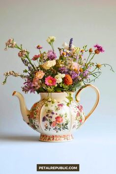 a tea pot filled with flowers on top of a table