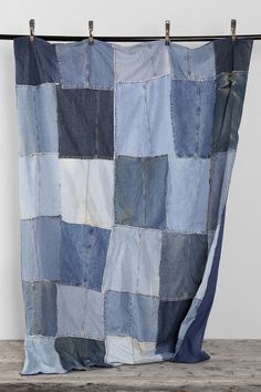 a blue and white patchwork quilt hanging on a clothes line with two pegs