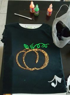 a t - shirt that has been sewn with beads on it and some scissors next to it