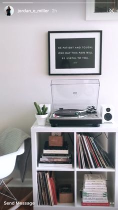 a record player sitting on top of a white book shelf next to a wall mounted poster