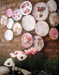 there are many plates on the wall and one is pink with flowers in front of it